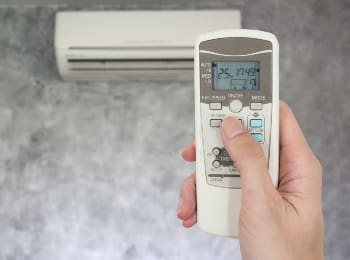 hand holding remote in front of air conditioner TMQE9W2